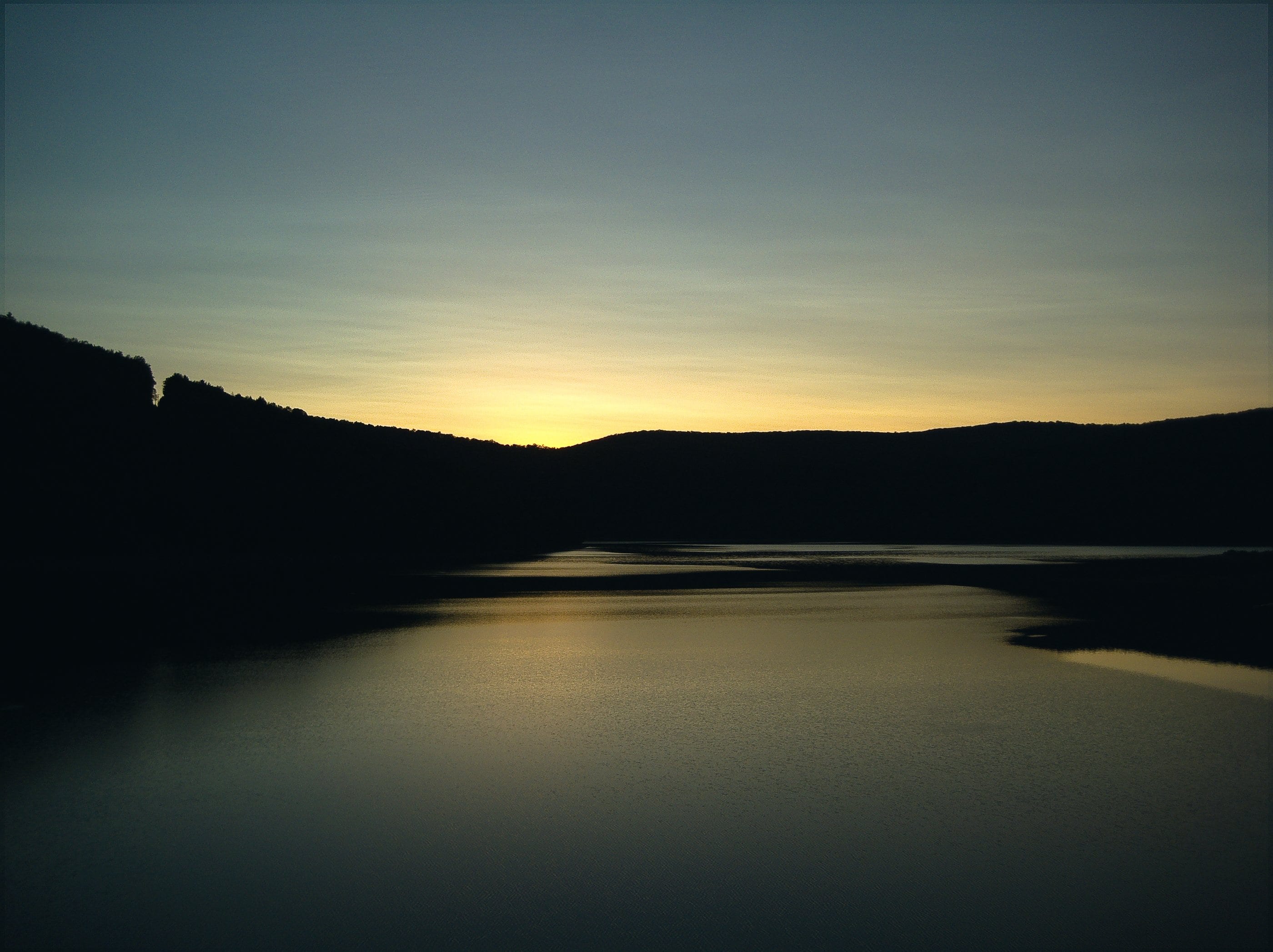 The Ashokan Reservoir at dusk, the hills dark against a fading sky and the water still.